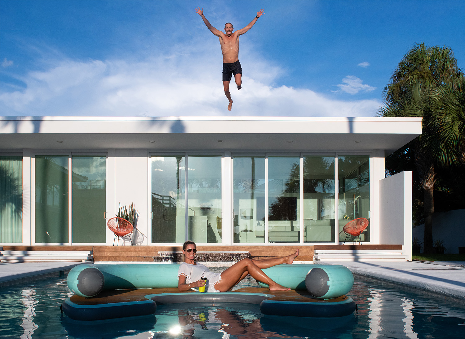 Corey Cooper jumps off the roof of his house into a pool below where Magda Cooper is floating on a raft
