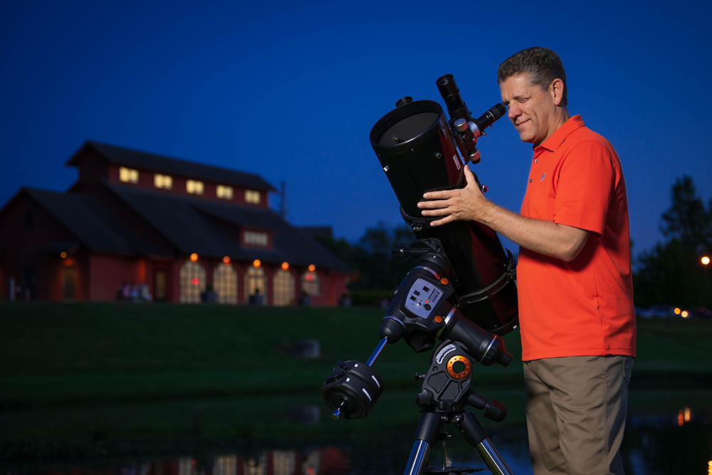 Middle age man looking through a telescope at night