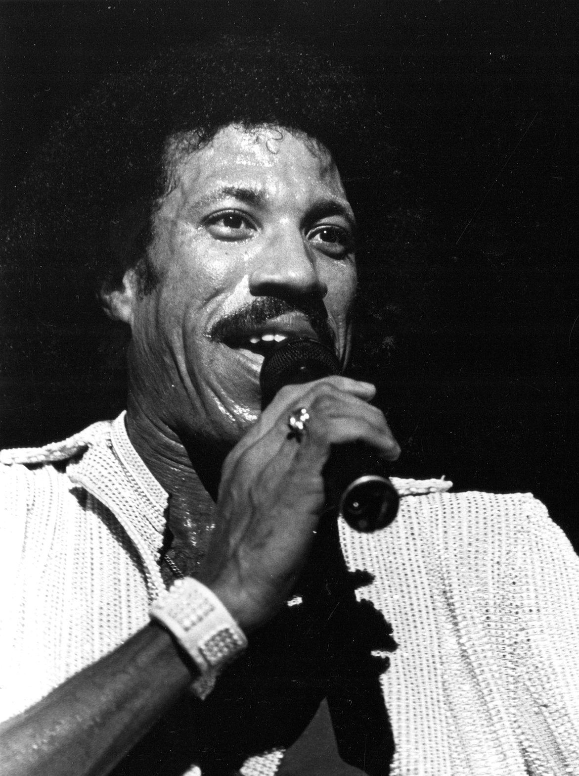 Lionel Richie on stage singing with microphone in his right hand