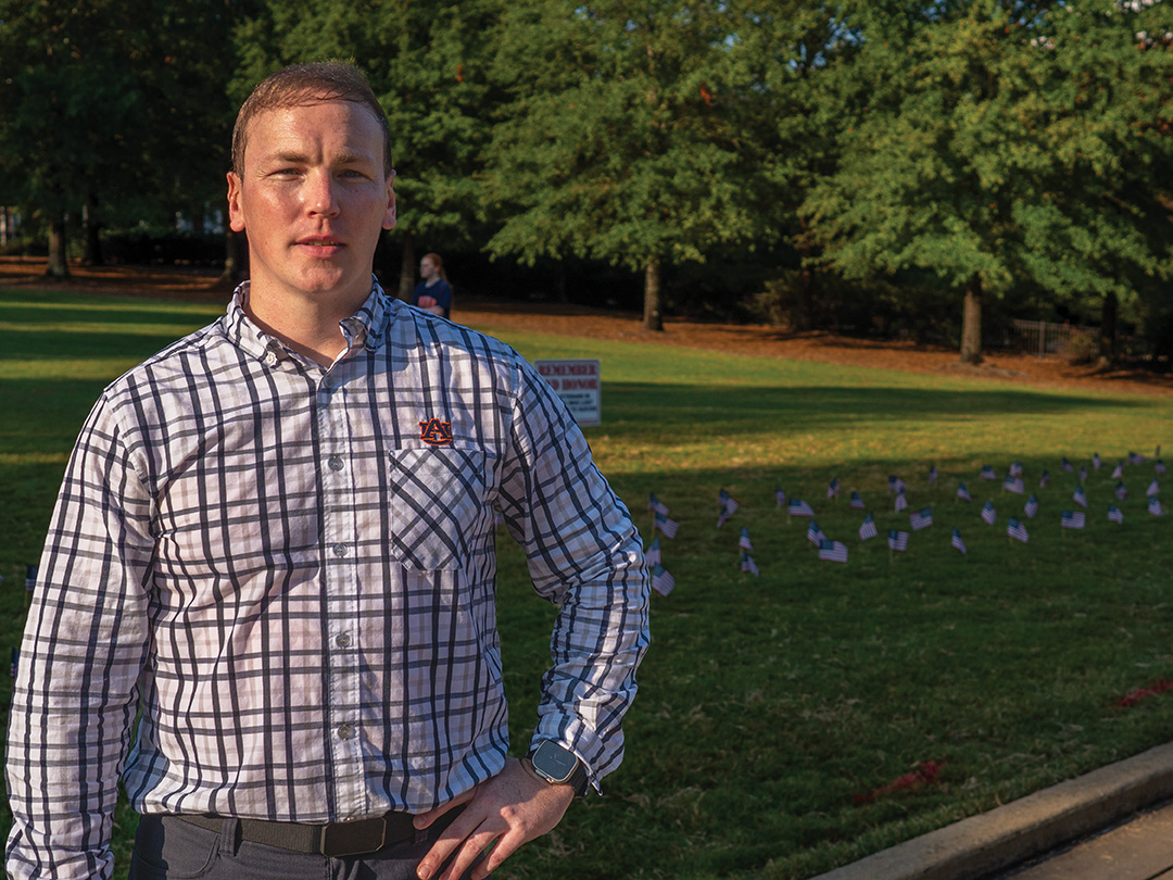 Young veteran stands in front of lawn decorated with American flags