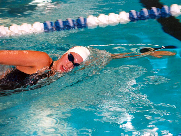 Female swimmer in a pool lap coming up for a breath of air while swimming